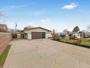 View of front of home with a garage, fence, and concrete driveway