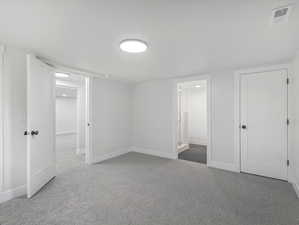 Unfurnished bedroom with carpet, baseboards, and visible vents