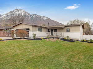 Ranch-style home with a garage, fence, a front yard, and a mountain view