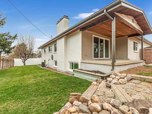 Back of property featuring a chimney, fence, brick siding, and a yard