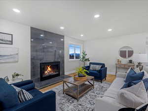 Living room with baseboards, a fireplace, light wood-style flooring, and recessed lighting
