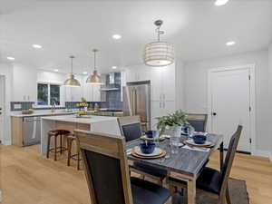 Dining space featuring light wood finished floors, baseboards, and recessed lighting