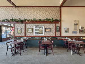 Dining room featuring carpet floors, ornamental molding, and wallpapered walls