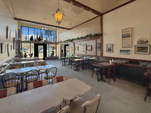 Dining space with carpet floors, a high ceiling, a chandelier, and french doors