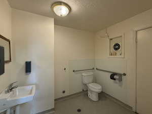 Half bathroom with a sink, a textured ceiling, and toilet
