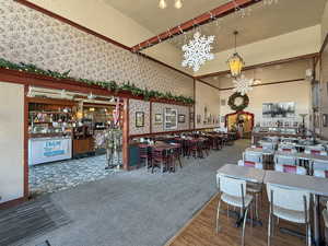 Dining space with wood finished floors, a towering ceiling, a textured ceiling, and wallpapered walls