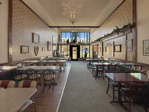 Dining space featuring a towering ceiling, an inviting chandelier, and wallpapered walls