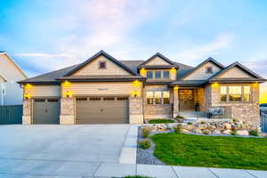 Craftsman inspired home with an attached garage, driveway, a front lawn, and stone siding
