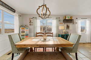 Dining room with a wainscoted wall, a textured ceiling, a decorative wall, visible vents, and a notable chandelier