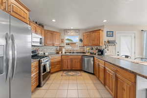Kitchen with a sink, dark countertops, appliances with stainless steel finishes, and brown cabinetry