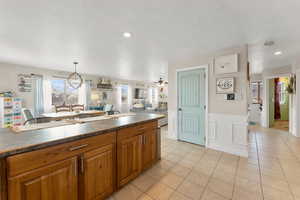 Kitchen with a textured ceiling, brown cabinets, dark countertops, and light tile patterned floors
