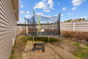 View of yard featuring a fenced backyard and a trampoline