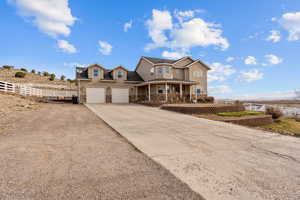 View of front of home with concrete driveway, fence, an attached garage, stone siding, and a porch