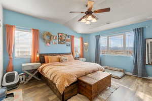 Bedroom with a textured ceiling, visible vents, wood finished floors, and vaulted ceiling
