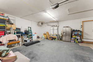 Garage with stainless steel fridge with ice dispenser and a garage door opener