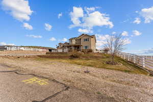 Rear view of house featuring uncovered parking and fence