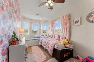 Bedroom featuring visible vents, baseboards, wood finished floors, a ceiling fan, and vaulted ceiling