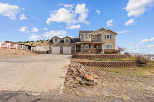 Traditional home featuring concrete driveway, fence, an attached garage, stone siding, and covered porch