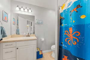 Bathroom with a shower with curtain, tile patterned flooring, vanity, toilet, and baseboards
