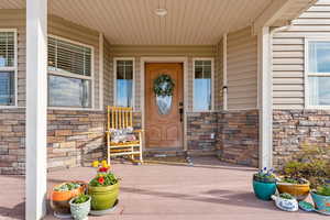 Doorway to property featuring covered porch and stone siding