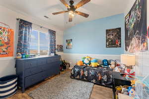 Bedroom with wainscoting, wood finished floors, lofted ceiling, and visible vents