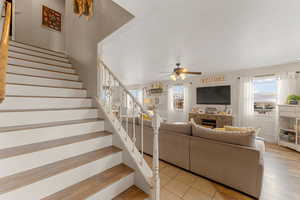 Living area featuring light wood finished floors, a textured ceiling, stairway, and a ceiling fan