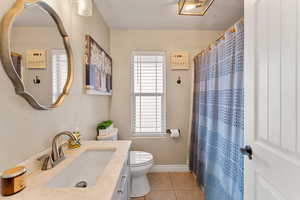 Full bath with baseboards, toilet, vanity, a shower with curtain, and tile patterned flooring