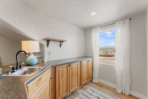 Kitchen featuring a sink, dark countertops, light wood-style floors, and open shelves