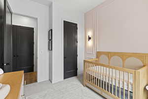 Bedroom with a crib and light carpet
