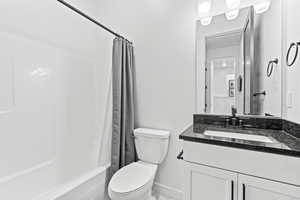 Full bathroom featuring vanity, toilet, baseboards, marble finish floor, and shower / bath combination with curtain