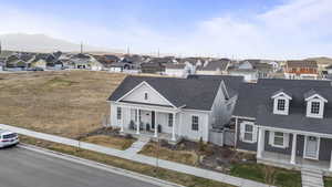 View of front facade featuring a residential view, a shingled roof, and covered porch