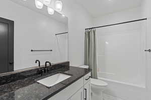 Bathroom featuring marble finish floor, toilet, vanity, and shower / bath combo with shower curtain
