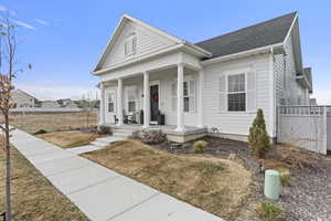 Greek revival inspired property with a front lawn, fence, a porch, and roof with shingles