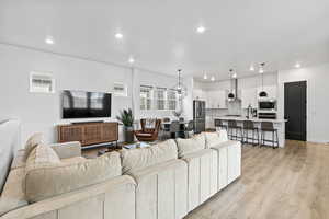 Living room featuring light wood-style flooring, recessed lighting, and an inviting chandelier