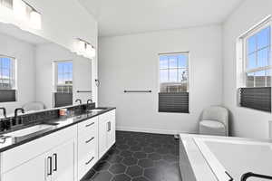 Full bathroom featuring tiled tub, a sink, and a healthy amount of sunlight