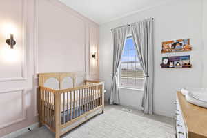 Bedroom featuring light carpet, baseboards, visible vents, and a nursery area