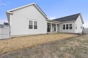 Rear view of property with a porch, fence, and a yard