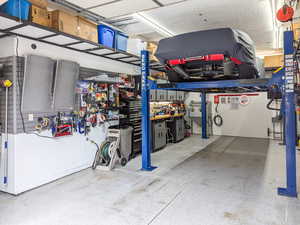 Single car garage with car lift, extra width and depth. Storage alongside walls and overhead.