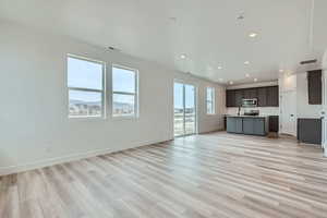 Unfurnished living room featuring baseboards, visible vents, light wood-style floors, and recessed lighting