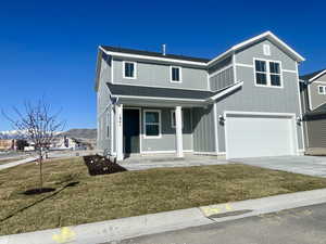View of front of home with covered porch, roof with shingles, a front yard, a garage, and concrete driveway