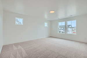 Unfurnished room with baseboards, visible vents, and light carpet