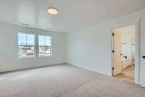 Carpeted empty room featuring baseboards and visible vents