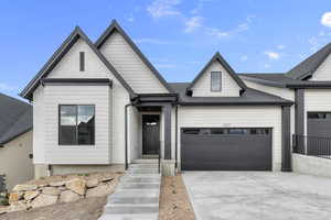View of front of home featuring an attached garage, a shingled roof, and concrete driveway