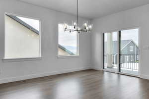 Empty room with baseboards, a chandelier, wood finished floors, and visible vents