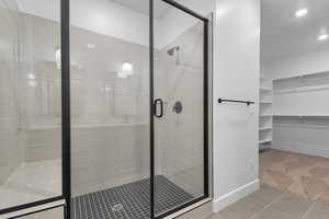 Bathroom featuring baseboards, a walk in closet, recessed lighting, tile patterned floors, and a stall shower