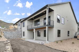 Rear view of property featuring a balcony, stucco siding, a patio area, a mountain view, and central air condition unit