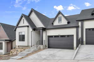 View of front of property with a garage, a shingled roof, and driveway