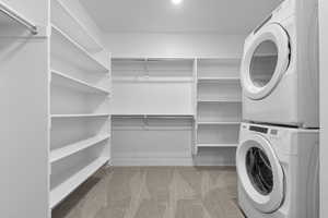 Laundry room featuring carpet floors, laundry area, and stacked washer / drying machine