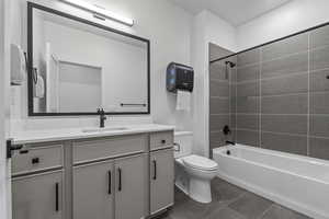 Bathroom with vanity, tile patterned flooring, shower / bathtub combination, and toilet