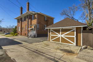 View of property exterior with an outdoor structure, a shingled roof, asphalt driveway, and a chimney. View of Garage